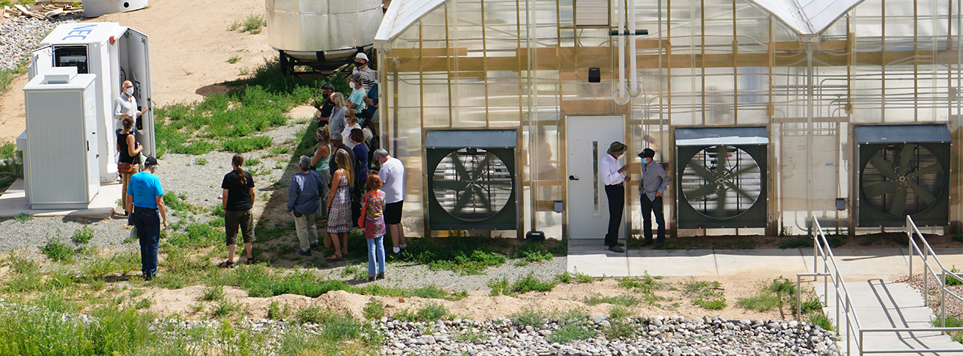 People standing outside a greenhouse listening to Frank Currie talk about the SFCC microgrid
