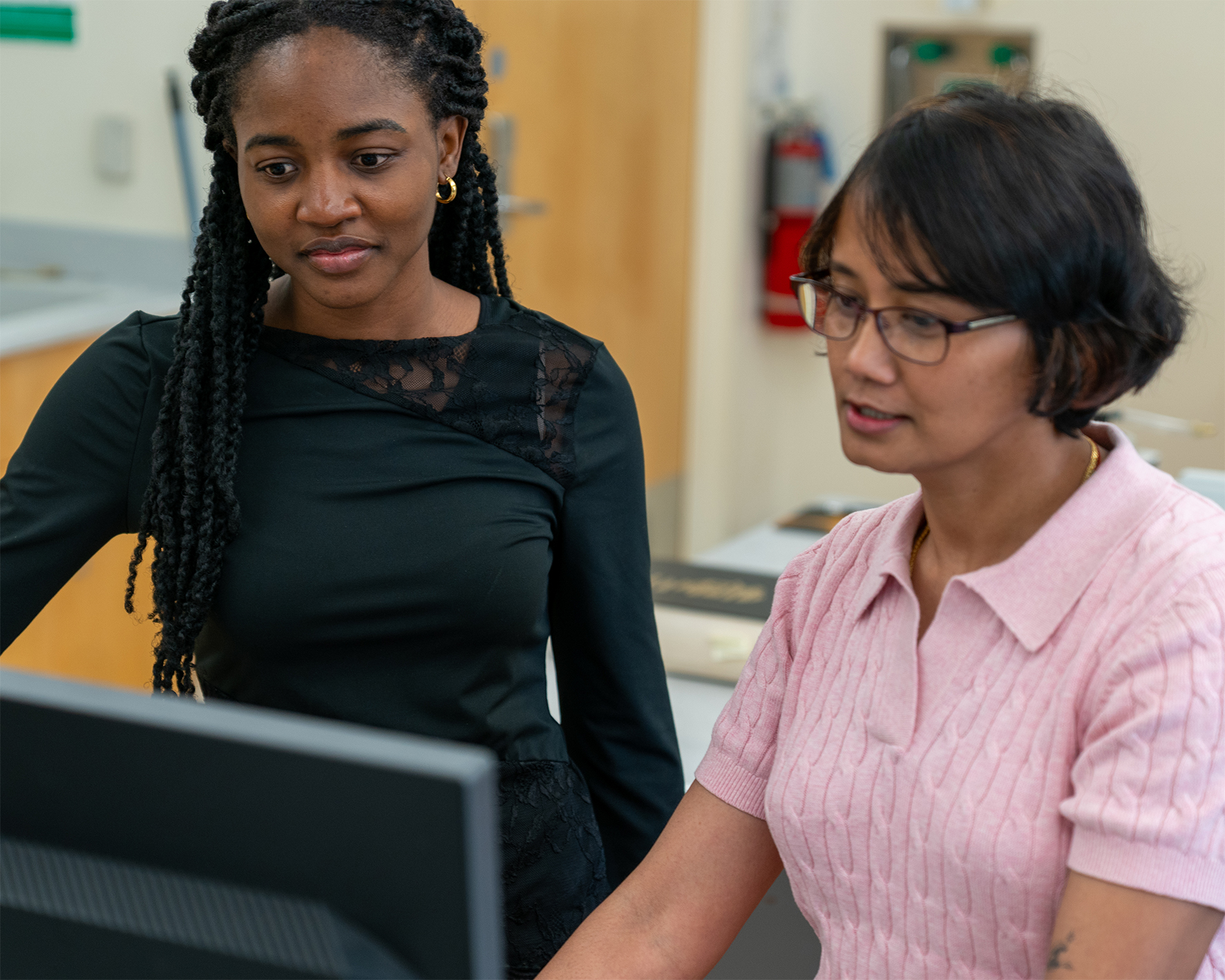 two woman doing research on a computer in lab