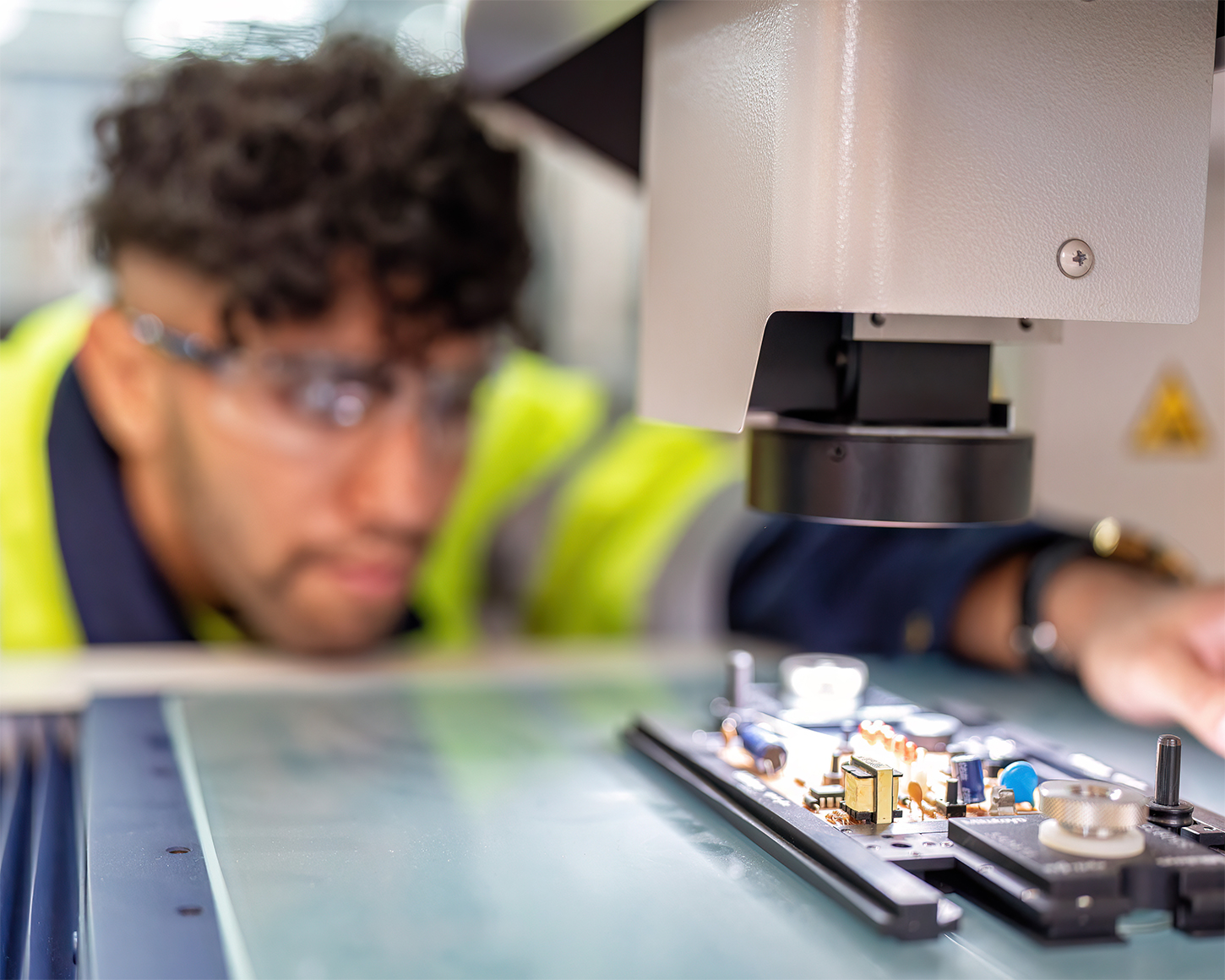 researcher looking at a circuit board under microscope