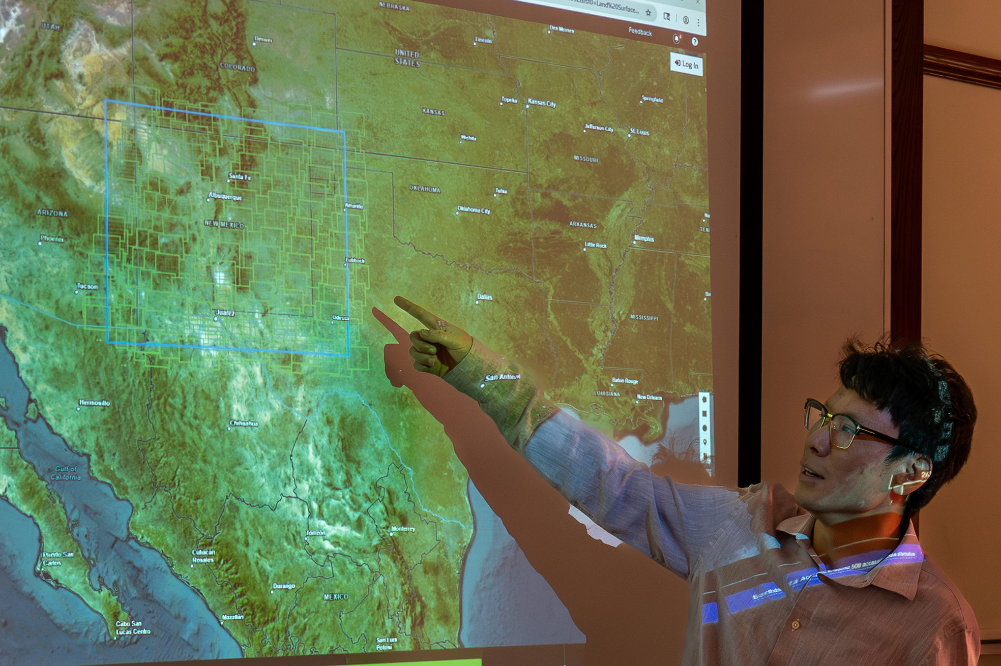 A man pointing at a map of the US on a projected screen